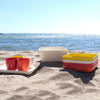 Orange, red, yellow, and white plates and cups and trays on beach