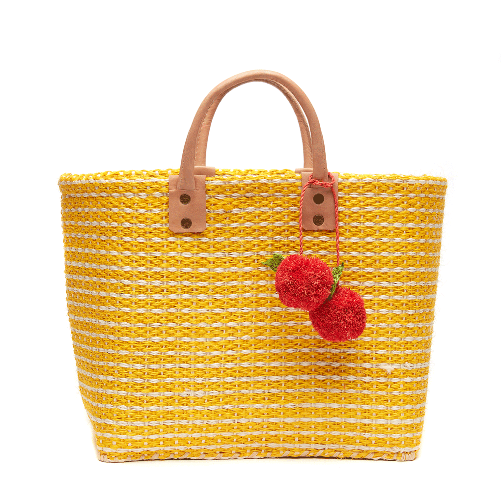 Hadley woven sisal beach tote in Sunflower yellow with cherry pom pom charms and leather handles