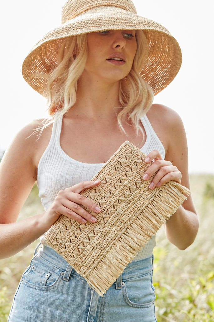 Model wearing natural colored crocheted sun hat with raffia tie