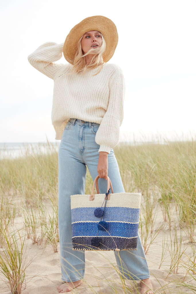Model holding three color navy sisal basket tote with removable poms & leather handles