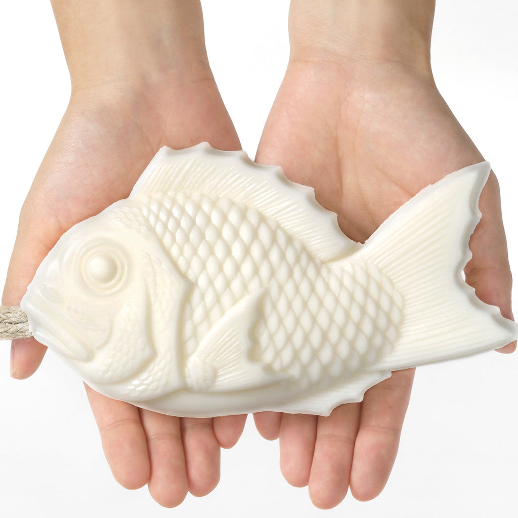 Hands holding white Tai fish soap with a rope handle
