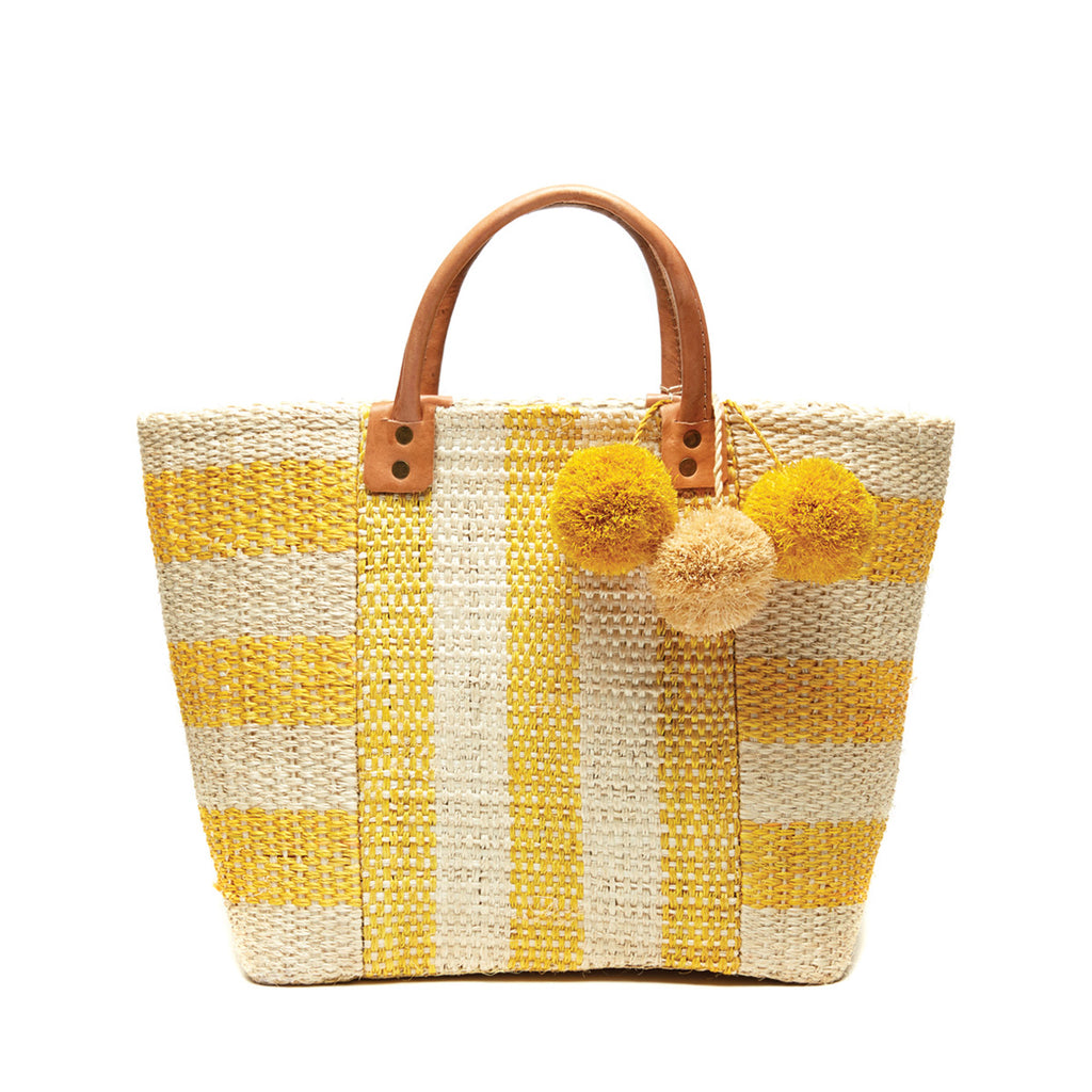 Yellow and natural striped woven sisal basket tote with pom poms and leather handles