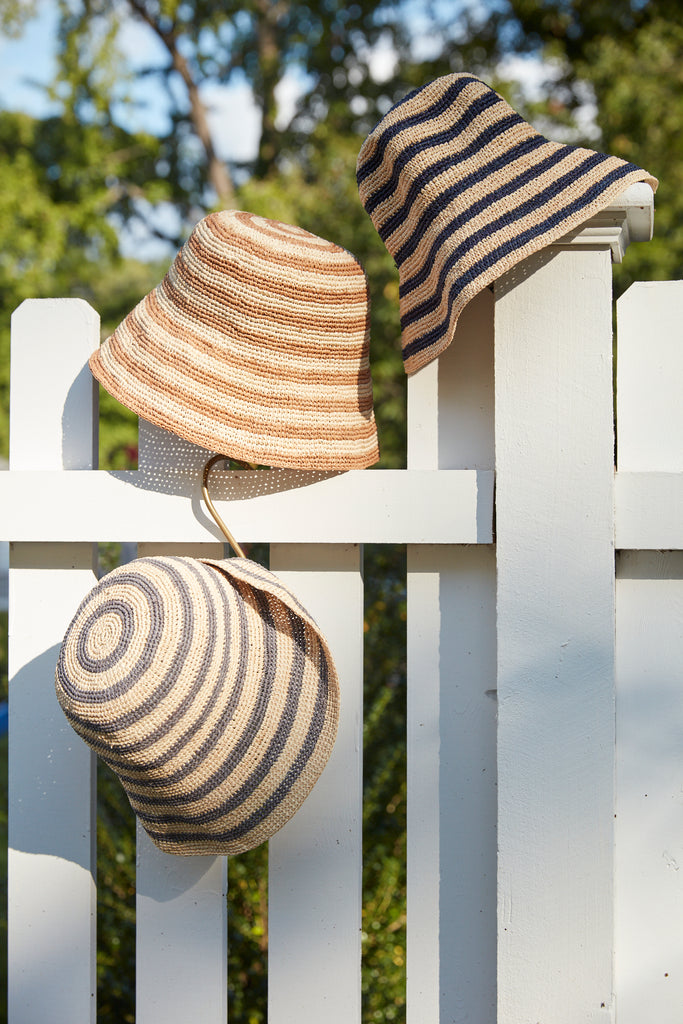 Three Eleni hats on a white fence