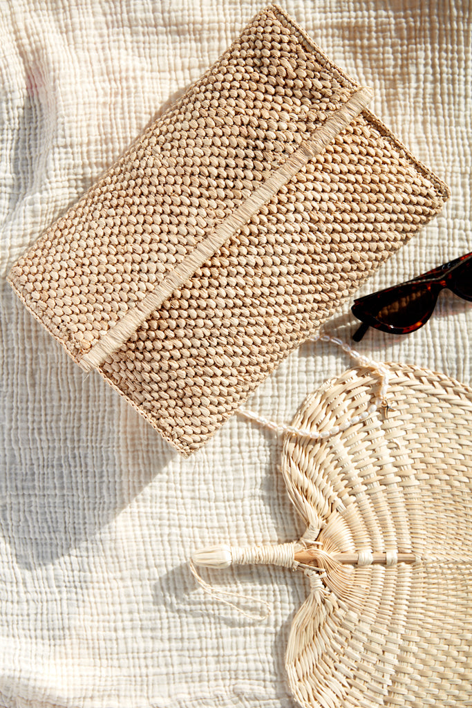 Rhodes clutch on a blanket with a fan and sunglasses