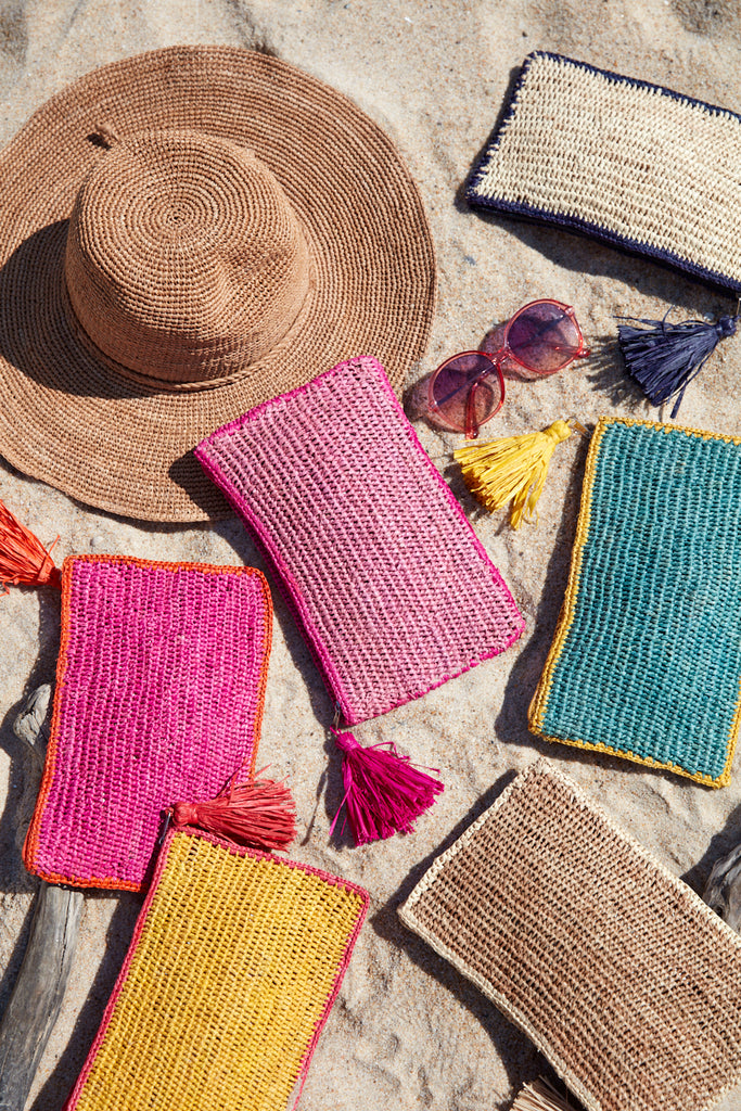 Assortment of Ellie pouches and a hat on the sand