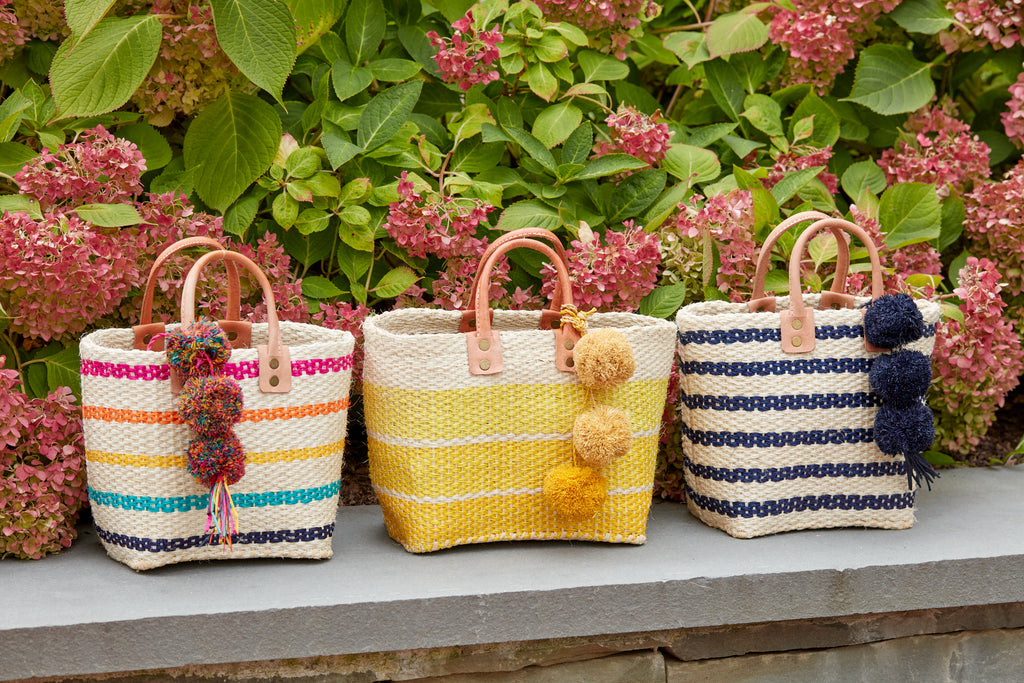 A trio of petite totes sitting on a stone wall with flowers