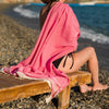 Crop of model on the beach wearing the pink Turkish towel