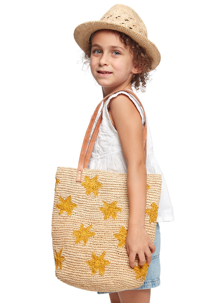 Avery Natural hat, woven Soleil tote bag with star patterns held by a person