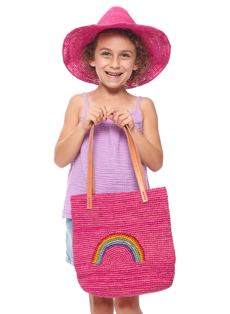 Person wearing pink Mika hat holding a pink bag with a rainbow design
