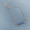 Bridge necklace displayed on a blue surface