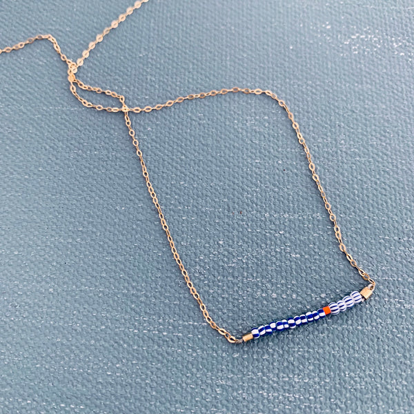 Bridge necklace displayed on a blue surface