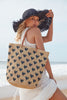 Model wearing navy colored fringed raffia sun hat with braided tie and navy Amelie tote