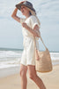 Model on the beach wearing our Mika raffia sun hat in Dove and our Augusta raffia tote in Natural