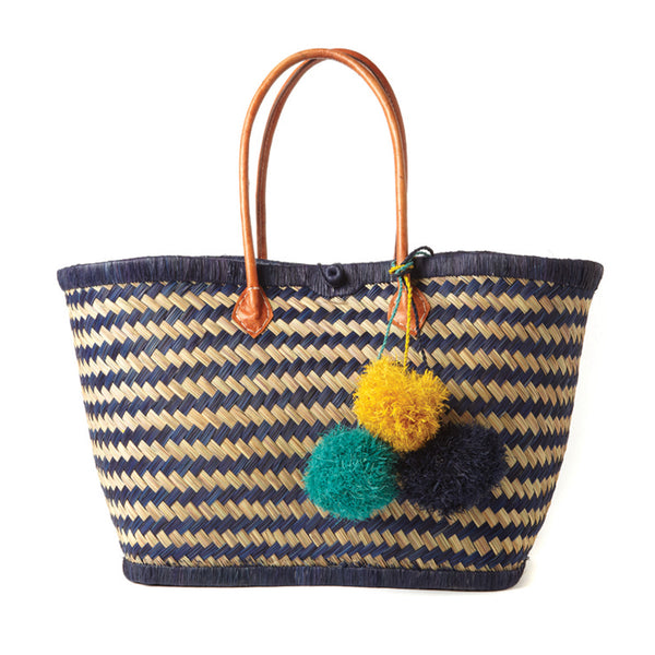 Navy and natural colored seagrass with raffia trim leather handles and tri-color pom poms.