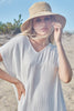 Model on the beach wearing our Bella raffia sun hat in Natural