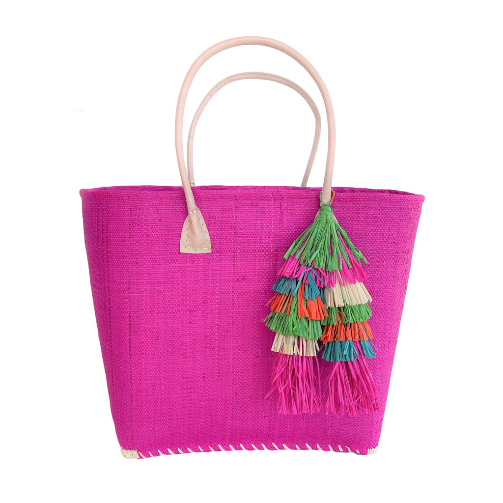 Pink colored woven seagrass and sisal tote with leather handles and multi colored tassel.