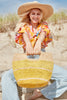 Model on the beach wearing our Camden raffia tote in Sunflower and our Jane raffia sun hat in Natural