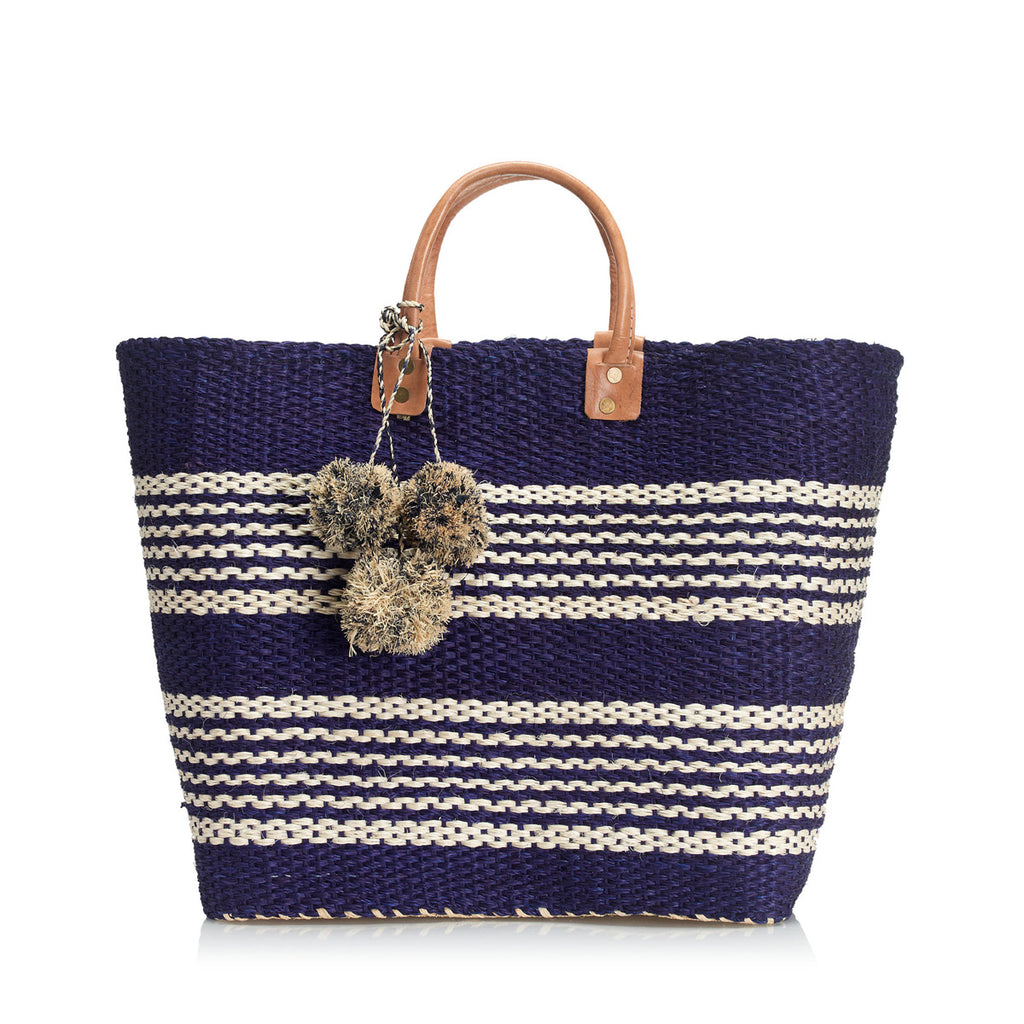 Navy colored woven sisal basket tote with white stripes and pom poms & leather handles