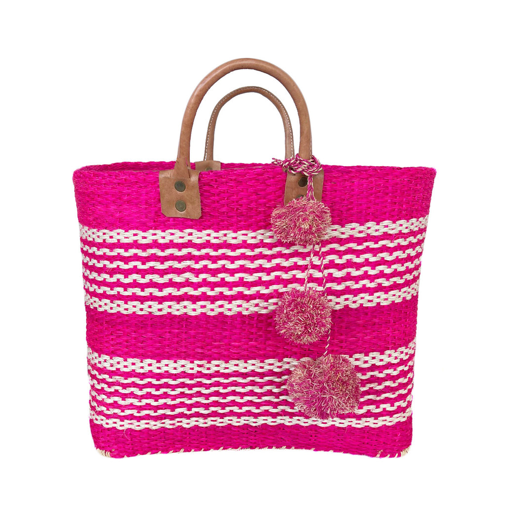 Pink colored woven sisal basket tote with white stripes and pom poms & leather handles