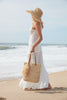 Model holding natural colored crocheted north-south tote with cotton lining, leather straps & removable tassel