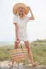 Model holding natural colored crocheted raffia shoulder tote with multi colored stripes,