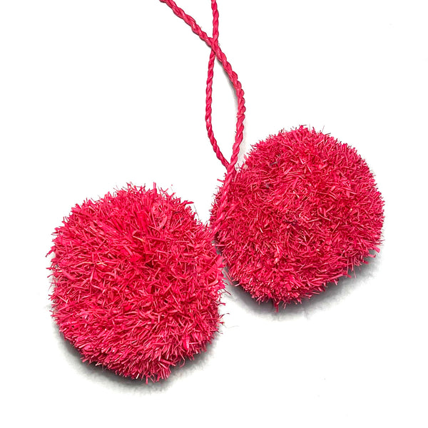 Two handmade pink raffia pom poms