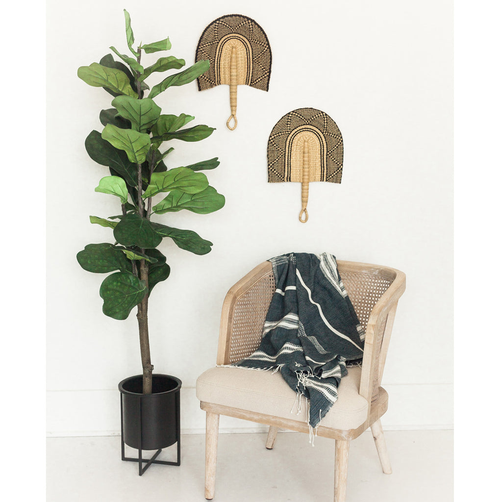 Pair of Bolga Fans in Black on a White Wall next to a wooden chair and potted plant