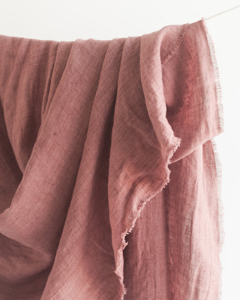 Woven linen throw in stonewashed rose draped over a line