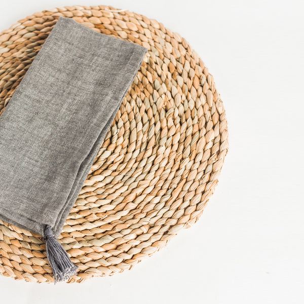 Handcrafted seagrass charger with grey napkin on it