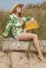 Model sitting on a log holding our Denise clutch in Sunflower
