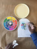 Vibrant water color set in a circular pallet, lid, and model painting flowers
