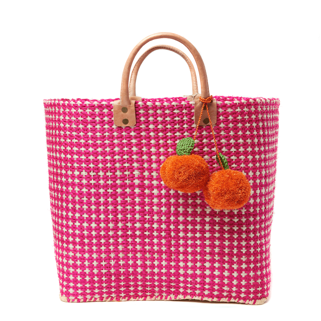 Hadley woven sisal beach tote in Pink with orange pom pom charms and leather handles