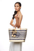 Model holding natural colored with navy pattern woven sisal basket tote with raffia tassels & leather handles