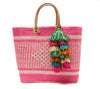 Woven sisal basket tote with leather handles and raffia tassels in Pink