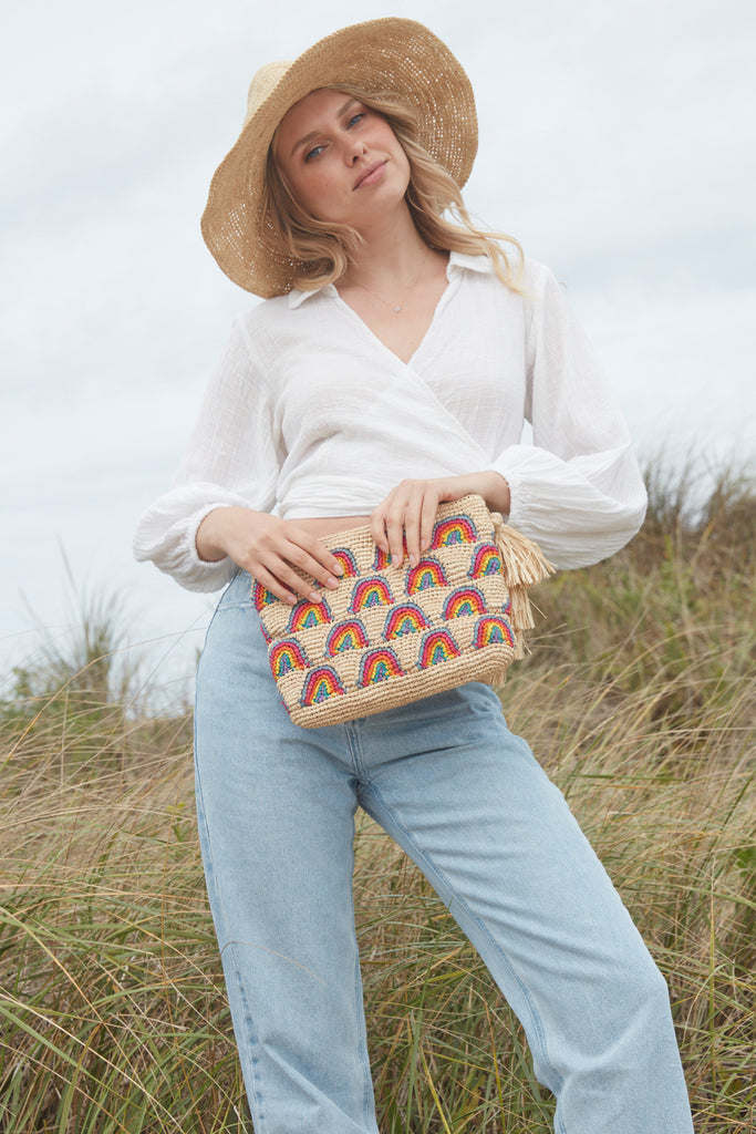 Model holding the Iris clutch in front of a grassy hill