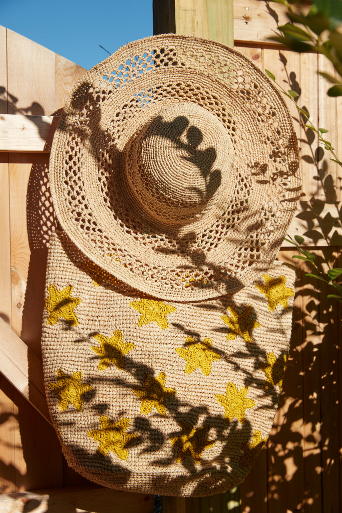 Sienna hat in Natural with Soleil tote on a wooden deck door