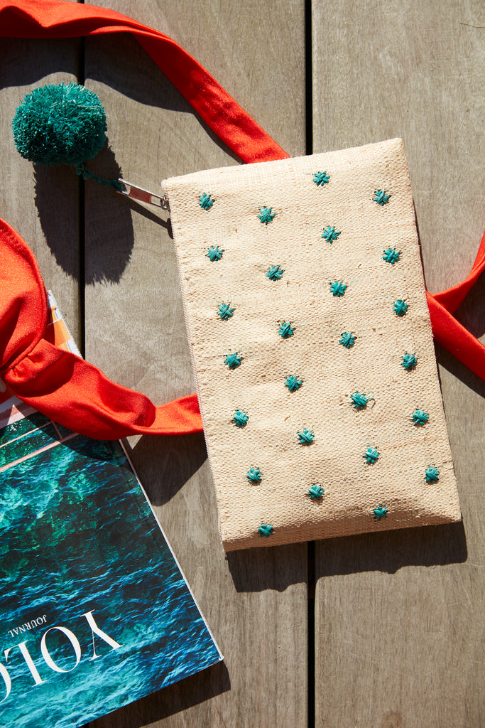 Sofia pouch in Aqua on a deck with a magazine and swimsuit