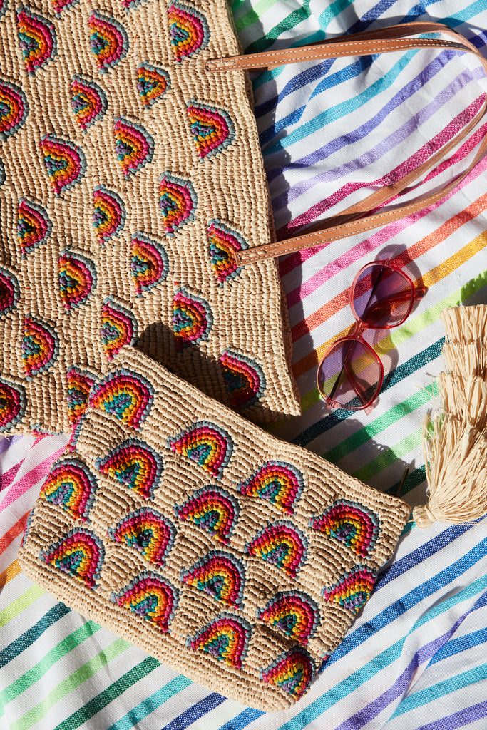 Iris tote and clutch on a rainbow beach blanket with sunglasses