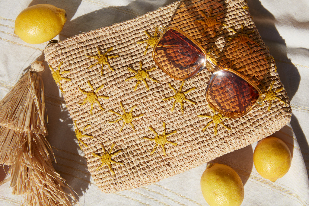 Soleil clutch on a towel with lemons and yellow sunglasses