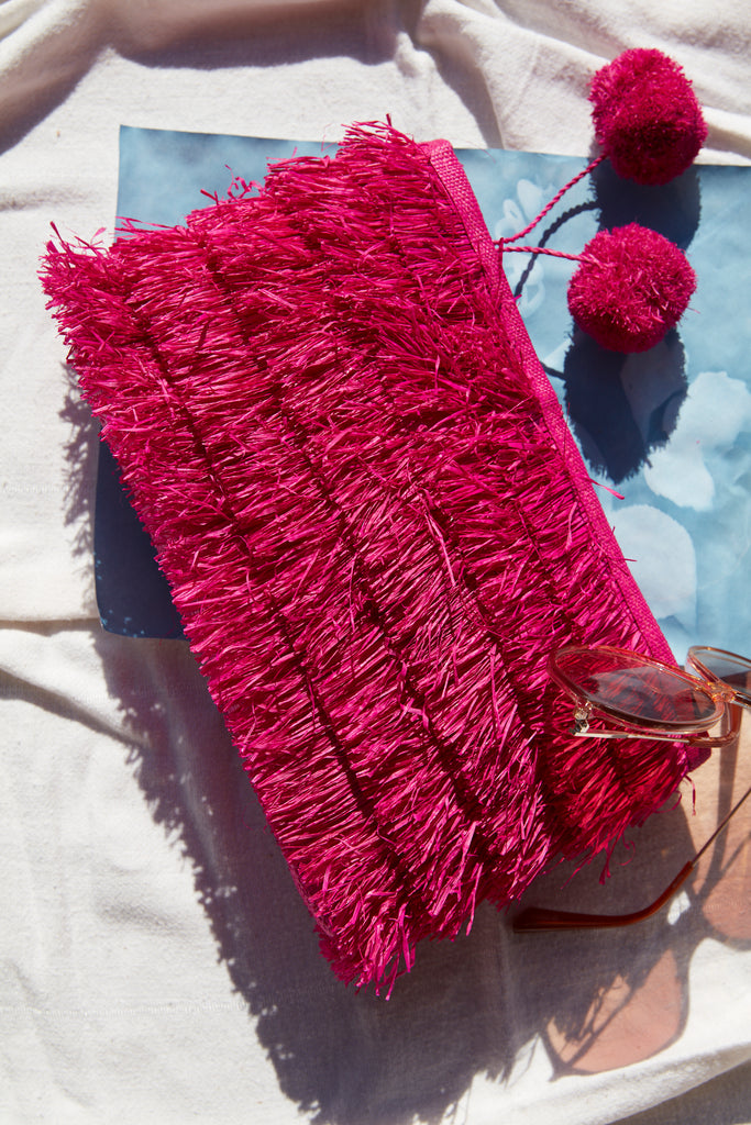 Sasha clutch in Pink on a beach towel with sunglasses