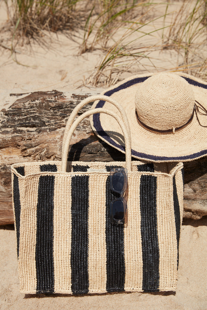 Roma tote in Navy Natural and Tori hat in Navy on a sandy beach