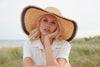 Crocheted raffia sun hat with leather trim and navy colored accent stripe around brim