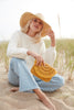 Model holding sunflower colored crocheted raffia pouch with cotton lining and snap closure