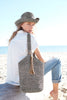 Model holding dove colored crocheted raffia shoulder bag with leather tassel & snap closure
