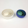 Nested set of white stoneware bowls next to a blue and green set