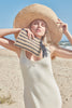Model on the beach with our Natalia sun hat and our Kyle raffia zip pouch in Navy