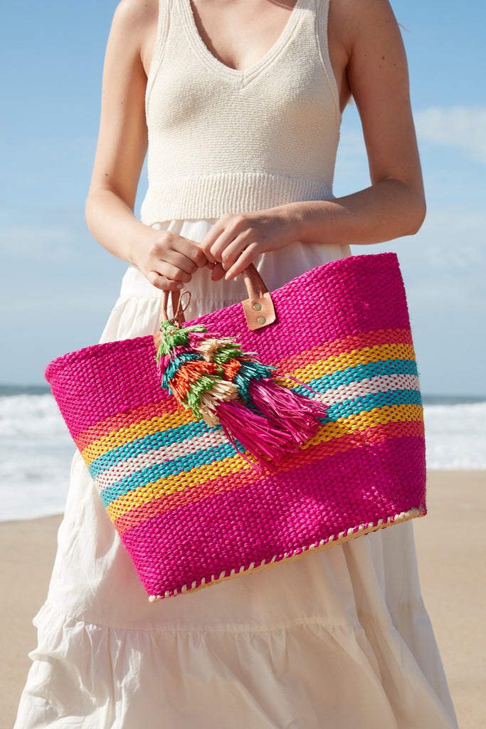 Model on the beach holding our La Paz sisal beach tote in Pink