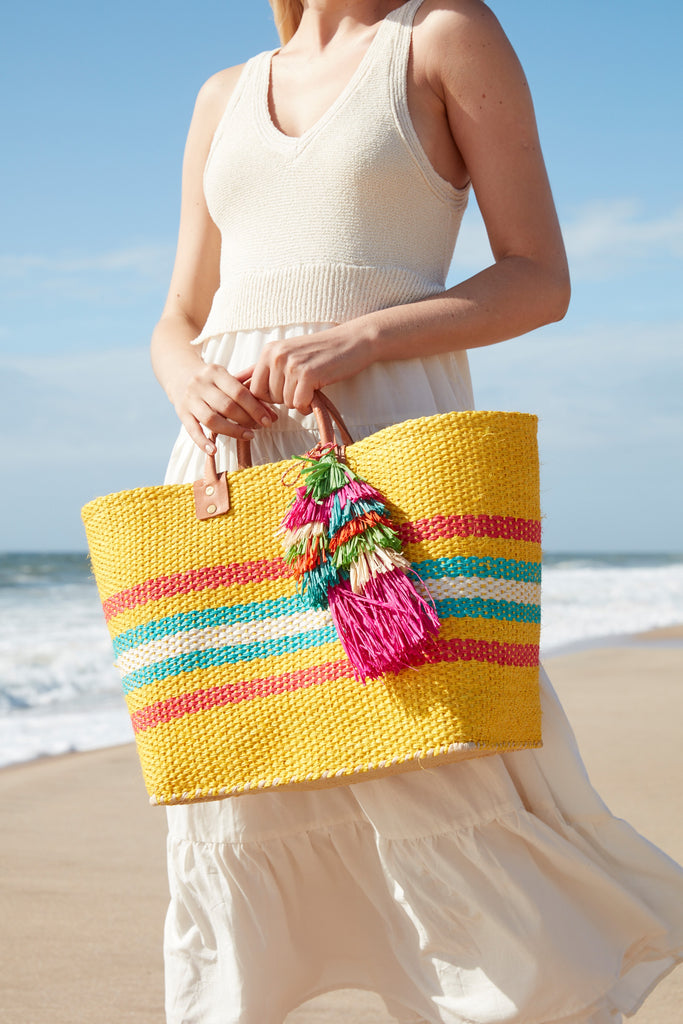 Model on the beach holding our La Paz sisal beach tote in Sunflower