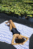 Model laying on white and blue striped beach blanket