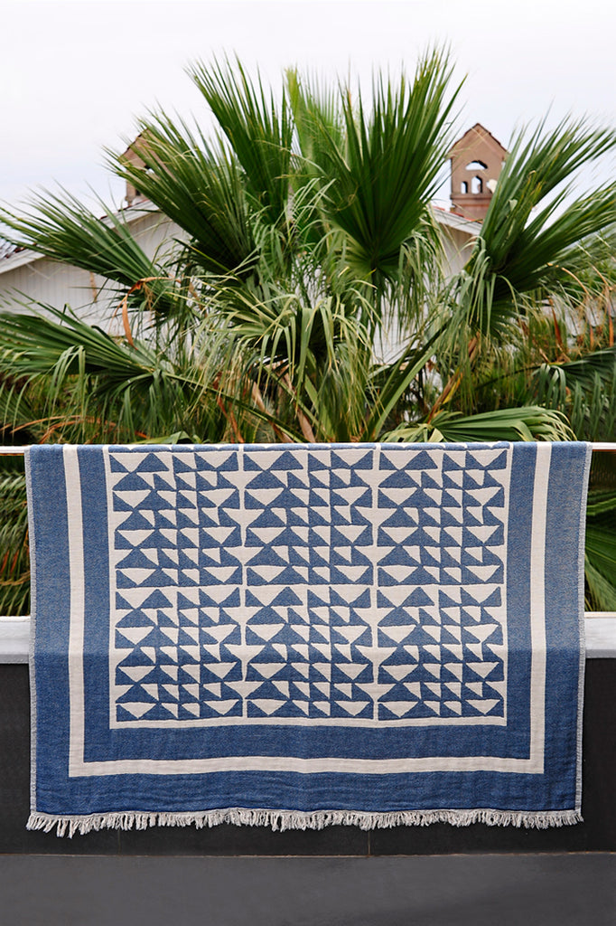 Hand woven Turkish cotton throw in marine and white hung on a railing
